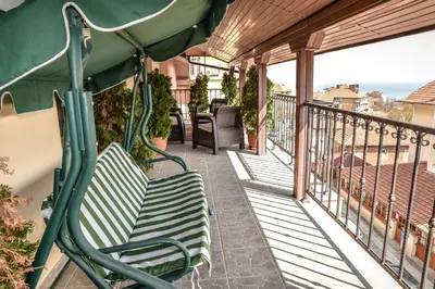 a porch with a green bench on a balcony at Dimitur Jekov Guest House in Obzor