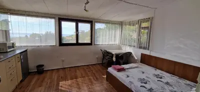 a bedroom with a bed and a kitchen with windows at Bungalow GHP-B in Varna City