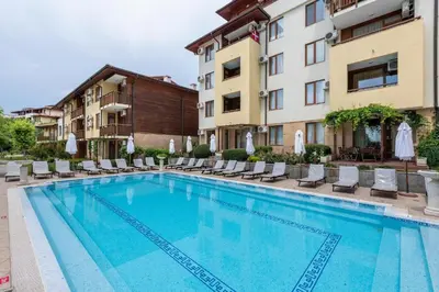 a large swimming pool with chairs and a building at Liliya in Sveti Vlas