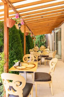 a patio with tables and chairs under a wooden pergola at Liliya in Sveti Vlas