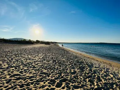 a sandy beach with a person walking along the water at Camping Gradina Garden Beach b33 in Chernomorets