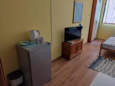 a living room with a refrigerator and a tv at Стая за гости на гр.Бургас in Burgas City