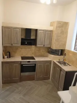 a kitchen with wooden cabinets and a stove and a sink at Апартаменти Стефанов in Varna City