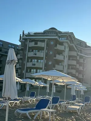 a group of chairs and umbrellas in front of a building at Penthouse Happy Moments in Sunny Beach