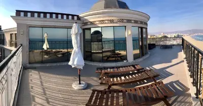 a deck with chairs and an umbrella on a building at Penthouse Happy Moments in Sunny Beach