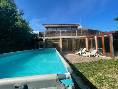 a swimming pool with two chairs and a house at DeTY’s Guest House in Drachevo
