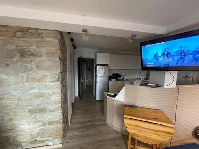 a kitchen with a stone wall and a tv on the wall at DeTY’s Guest House in Drachevo