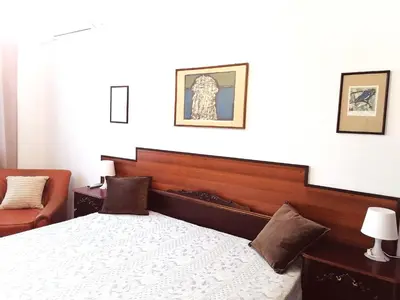 a bedroom with a bed with a wooden head board at Оазис 1 във Варна in Varna City