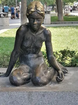a statue of a young boy sitting on the ground at Оазис 2 във Варна in Varna City