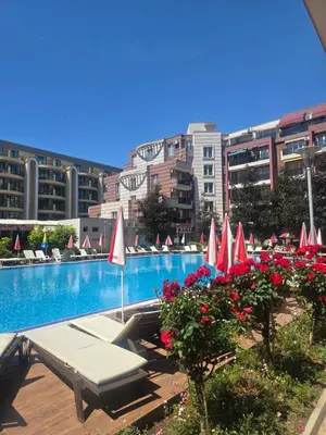 a swimming pool with red and white umbrellas and flowers at Deluxe Admiral Plaza in Sunny Beach