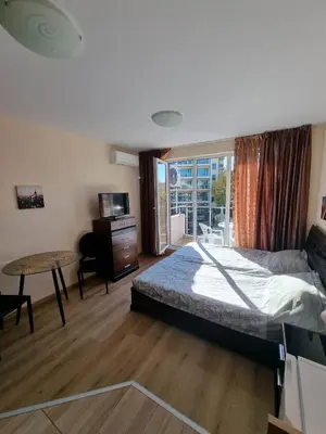 a bedroom with a bed and a table and a window at Deluxe Admiral Plaza in Sunny Beach