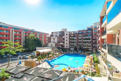 an outdoor swimming pool with chairs and umbrellas and buildings at Deluxe Admiral Plaza in Sunny Beach