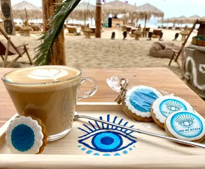 a cup of coffee and cookies on a table near the beach at Infinity View Shkorpilovci in Shkorpilovtsi
