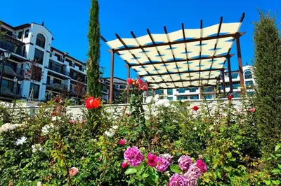 a garden with flowers in front of a building at Boutique Rose Gardens Pomorie in Pomorie