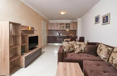 a living room with a couch and a television at Boutique Rose Gardens Pomorie in Pomorie