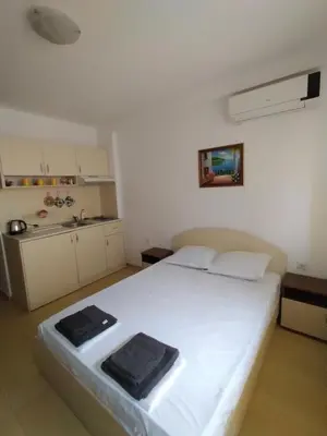 a bedroom with a white bed and a kitchen at Жасмин клуб in Sunny Beach