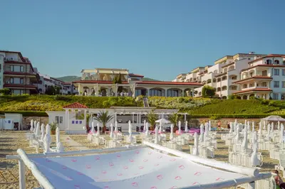 a swimming pool with chairs and tables and buildings at Grande Mia Casa in Sveti Vlas