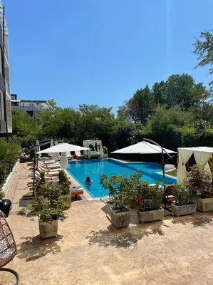 a swimming pool with potted plants and umbrellas at Deluxe Apartments Приморско in Primorsko