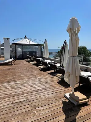a row of lounge chairs and an umbrella on a deck at Deluxe Apartments Приморско in Primorsko