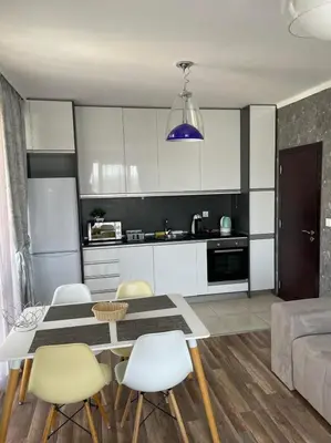 a kitchen and living room with a table and chairs at Deluxe Apartments Приморско in Primorsko