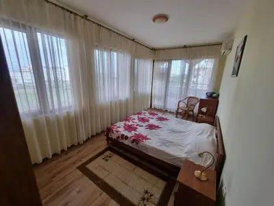 a bedroom with a bed and some windows and a chair at Sunrise Splendid in Obzor
