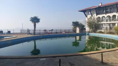 a swimming pool in front of a building and the ocean at Monastery II Garden stay like home in Sveti Vlas