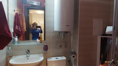 a woman taking a picture of a bathroom with a sink at Monastery II Garden stay like home in Sveti Vlas