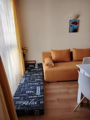 a living room with a couch with a blanket on the floor at Ваканционно студио Аквария in Sunny Beach