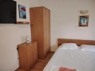 a bedroom with a bed and a wooden cabinet at Ваканционно студио Аквария in Sunny Beach