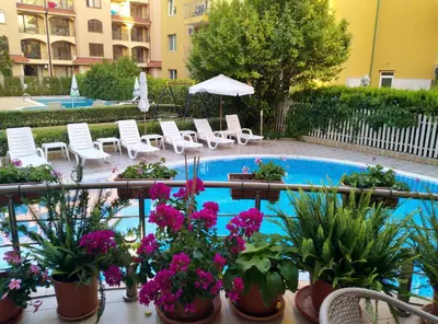 a swimming pool with chairs and potted plants at Ваканционно студио Аквария in Sunny Beach
