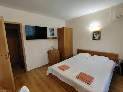 a bedroom with a white bed and a flat screen tv at Ваканционно студио Аквария in Sunny Beach