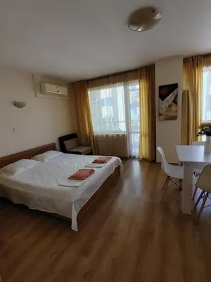 a bedroom with a bed and a table and chairs at Ваканционно студио Аквария in Sunny Beach