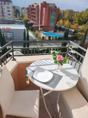 a table with a vase of flowers on a balcony at Afrodita Palas , studio appartment 4 floor, pool view in Sunny Beach