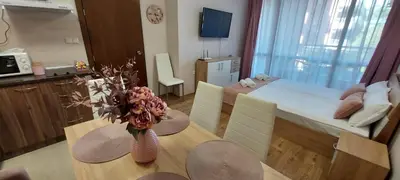 a kitchen and dining room with a table with flowers on it at Студио Ервина in Ravda