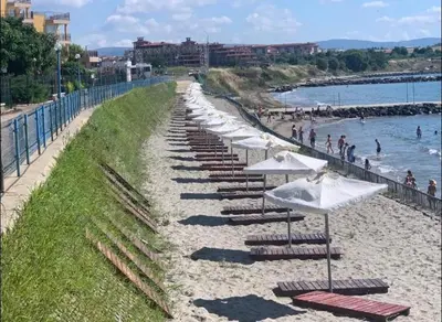 a row of lounge chairs and umbrellas on a beach at Midia Family Resort, Aheloy in Aheloy