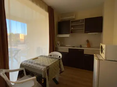 a small kitchen with a table and a refrigerator at VECHNA R 18 Studio Sunny Beach in Sunny Beach