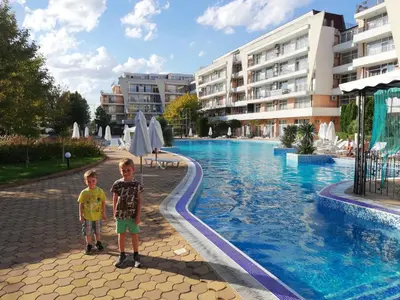 two young boys standing next to a swimming pool at Apartment Daisy Grand Kamelia in Sunny Beach