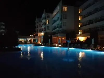 an empty swimming pool at night with buildings at Apartment Daisy Grand Kamelia in Sunny Beach