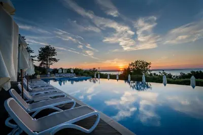 a swimming pool with lounge chairs and a sunset at Eve Santa Marina Apartments II - sea, pools, relax in Sozopol