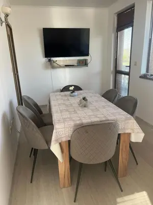 a dining room table with chairs and a television at Частен апартамент Стамополу - Private Two-Bedroom Apartment Stamopolu in Primorsko
