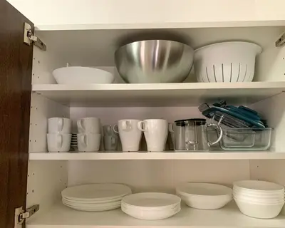 a cupboard filled with white dishes and bowls at Todorka Sunny View Central w Słonecznym Brzegu in Sunny Beach