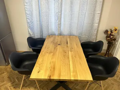 a wooden table with four chairs in front of a curtain at Niya Apartment Bourgas in Burgas City
