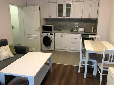 a kitchen with white cabinets and a table and chairs at Purple Rose Apartment Valencia Gardens in Nesebar