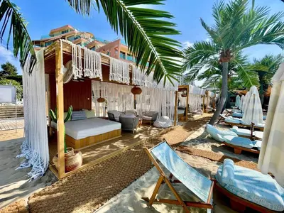 a hotel room with a bed and chairs and palm trees at Luxurious 2 BR Appt at the Black Sea Coast in Sunny Beach