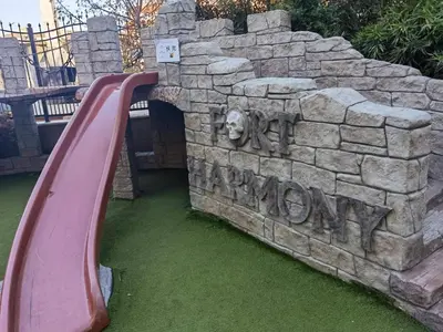 a red slide in a stone wall with a lion on it at Harmony Suitеs apartment in Sunny Beach