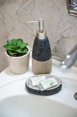 a bathroom sink with a soap dispenser and a plant at Lovely Art apartment - Victory in Varna City