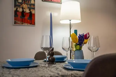 a table with plates and glasses and flowers on it at Lovely Art apartment - Victory in Varna City