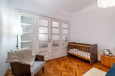 a white room with a crib and some windows at Lovely Art apartment - Victory in Varna City