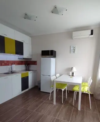 a kitchen with a table and chairs and a refrigerator at Apartments SunWave Saint Vlas in Sveti Vlas