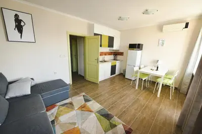 a living room with a couch and a table and a kitchen at Apartments SunWave Saint Vlas in Sveti Vlas
